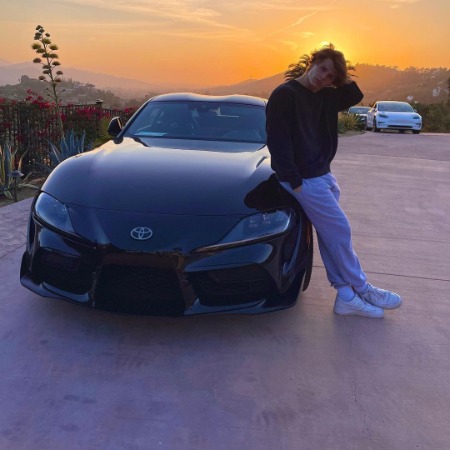 Sam Dezz posing with his luxurious black Toyota Supra in beautiful sunset.